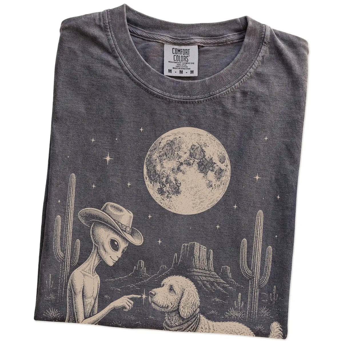 Folded Pepper Comfort Colors® T-shirt showing cowboy alien fist-bumping a goldendoodle beneath the moon