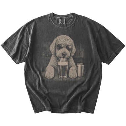 Goldendoodle sneaking a drink from a foamy pint at home on a Pepper Comfort Colors® t-shirt