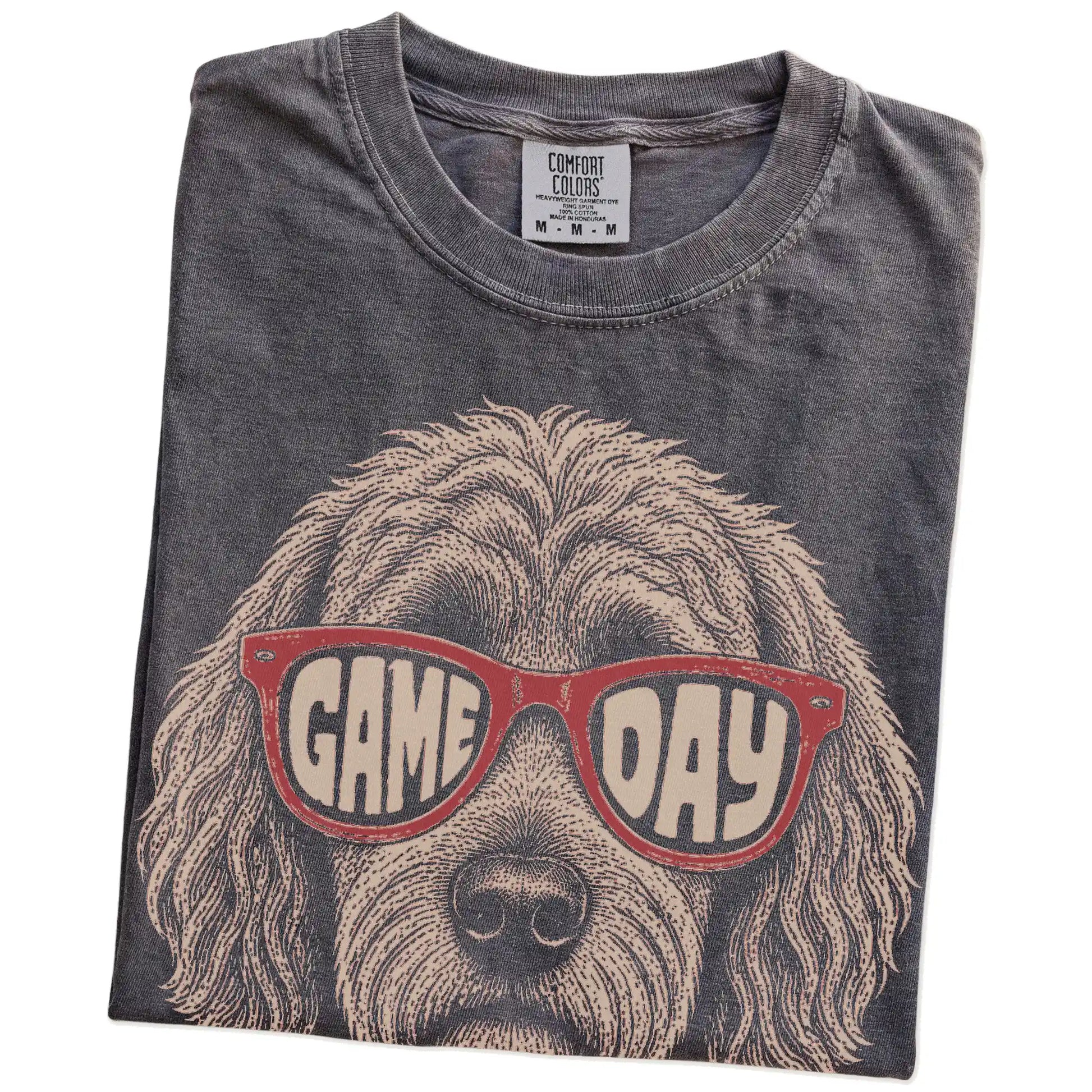 Folded Pepper Comfort Colors® T-shirt showing goldendoodle wearing red game day sunglasses