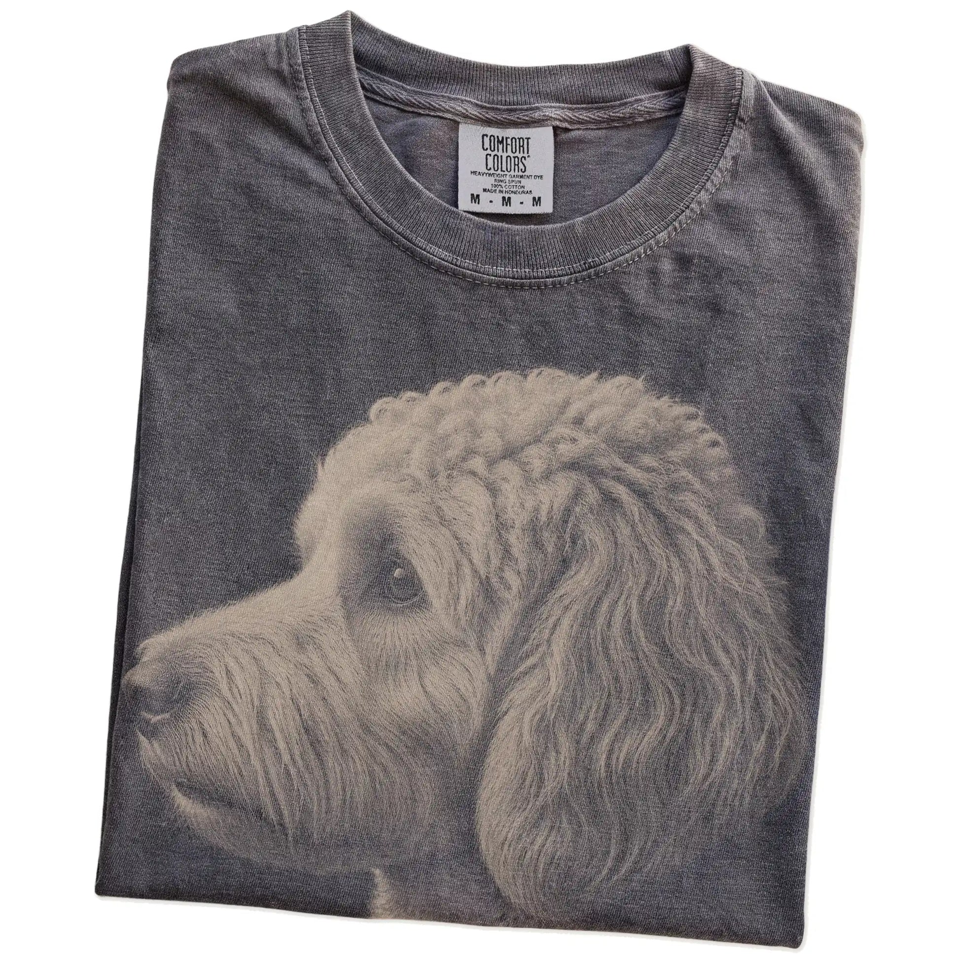 Folded Pepper Comfort Colors® T-shirt showing a detailed photographic portrait of a Goldendoodle