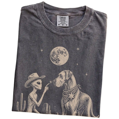 Folded Pepper Comfort Colors® T-shirt showing cowboy alien fist-bumping a great dane beneath the moon