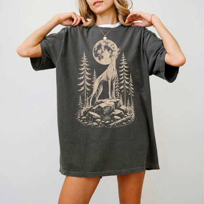 Model wearing a Pepper Comfort Colors® T-shirt with a Greyhound howling beneath the moon and pine trees