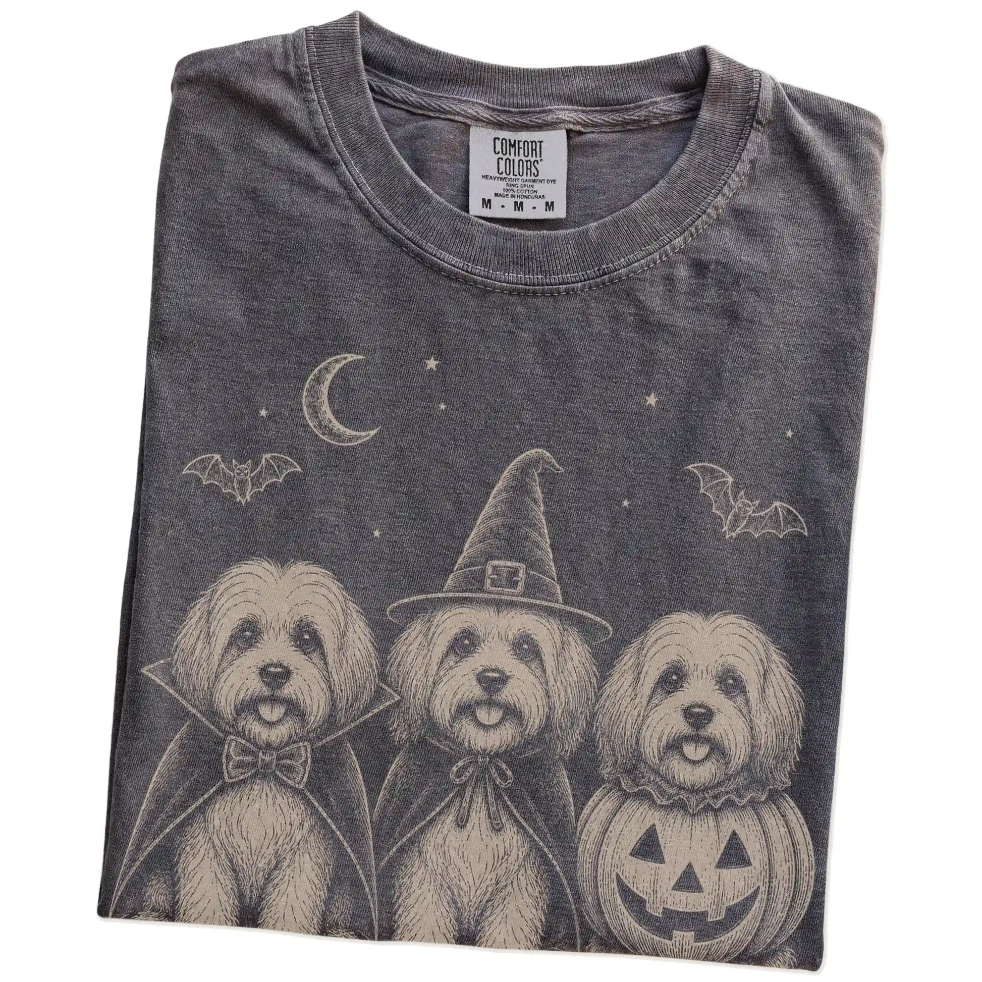 Folded Pepper Comfort Colors® T-shirt showing three Havanese dogs dressed for Halloween beneath bats and a crescent moon
