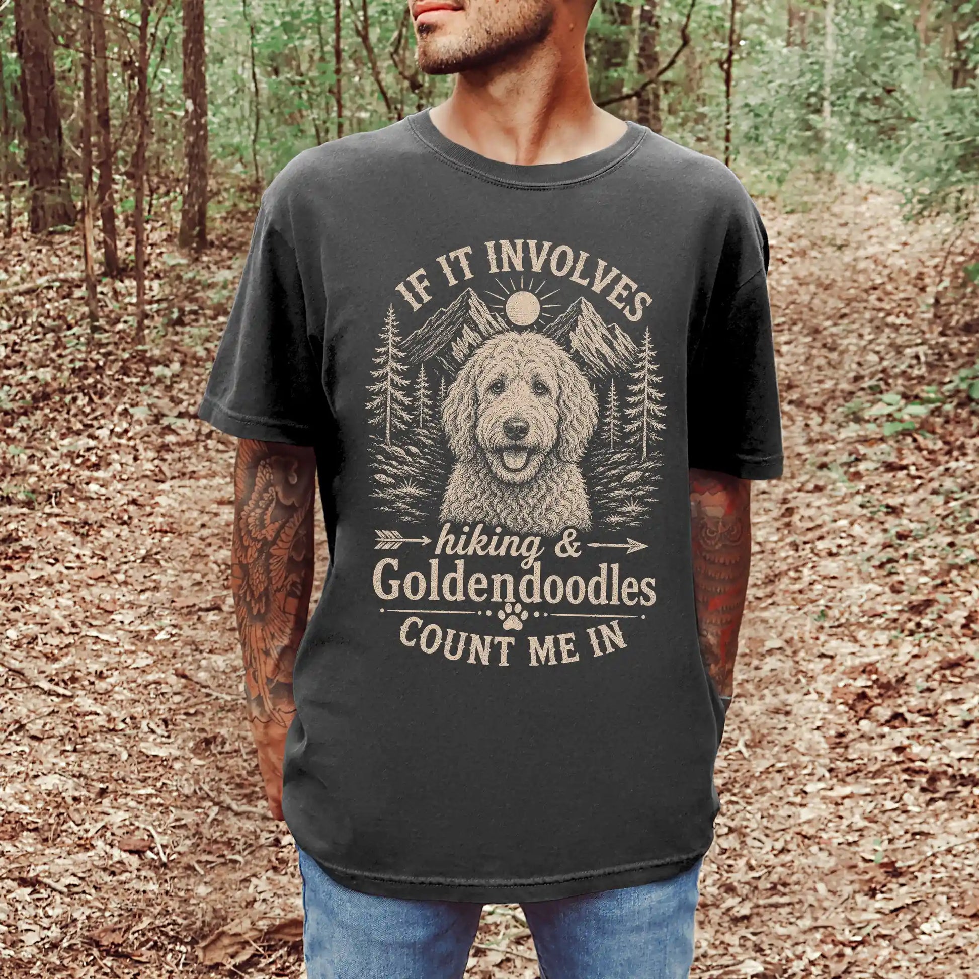 Model wearing a Pepper Comfort Colors® T-shirt featuring Goldendoodle hiking design with mountain scenery