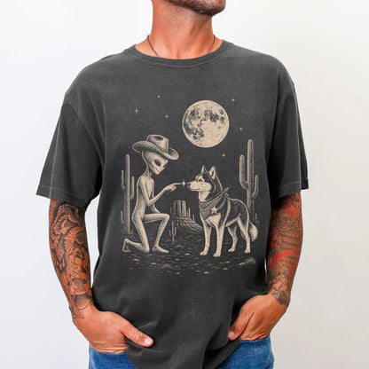 Model wearing a Pepper Comfort Colors® T-shirt with cowboy alien fist-bumping a husky beneath the moon