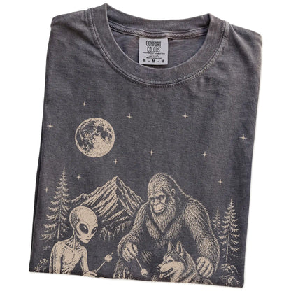 Folded Pepper Comfort Colors® T-shirt showing Husky camping with Bigfoot and an alien