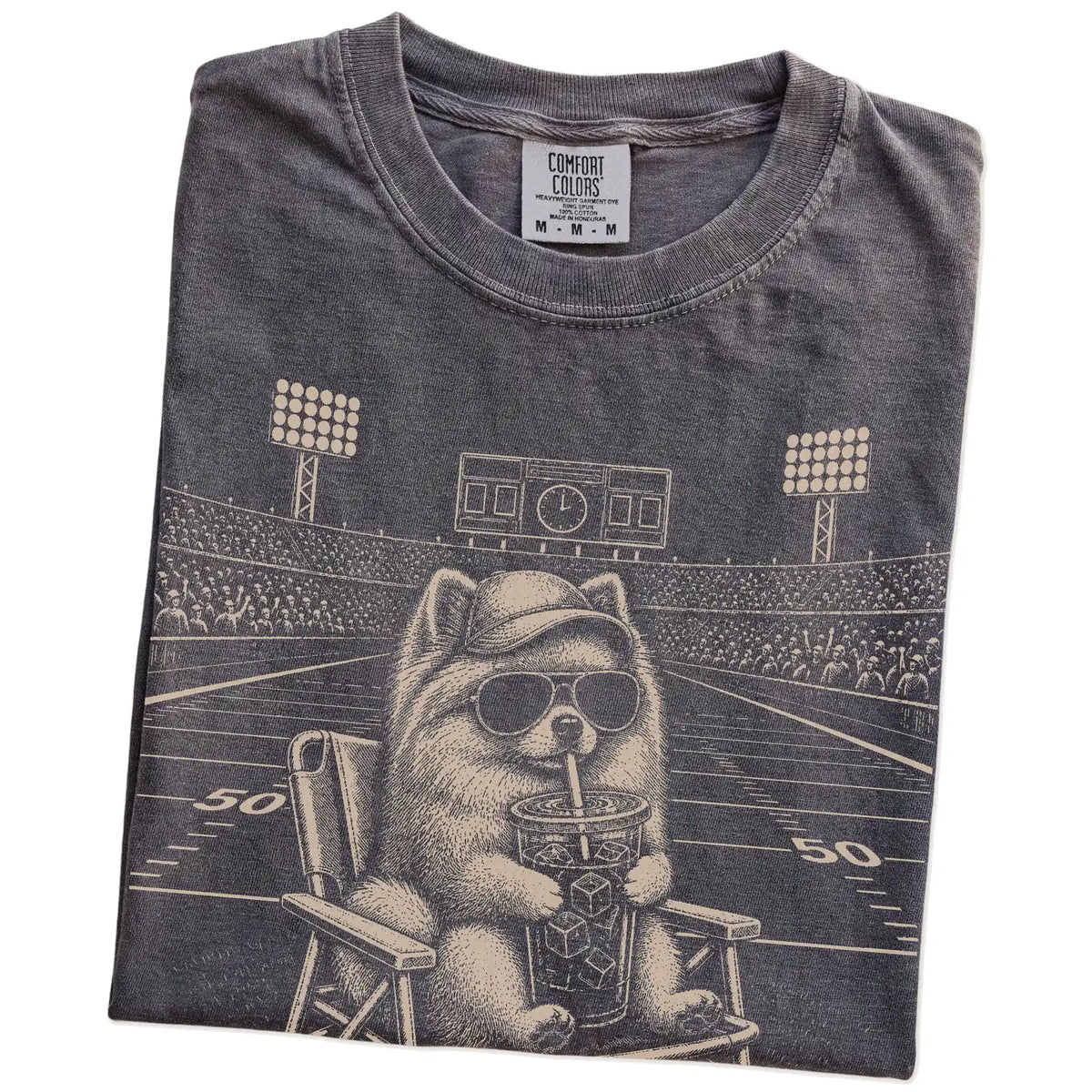 Folded Pepper Comfort Colors® T-shirt showing Pomeranian claiming the football field with “I Live Here Now” lettering