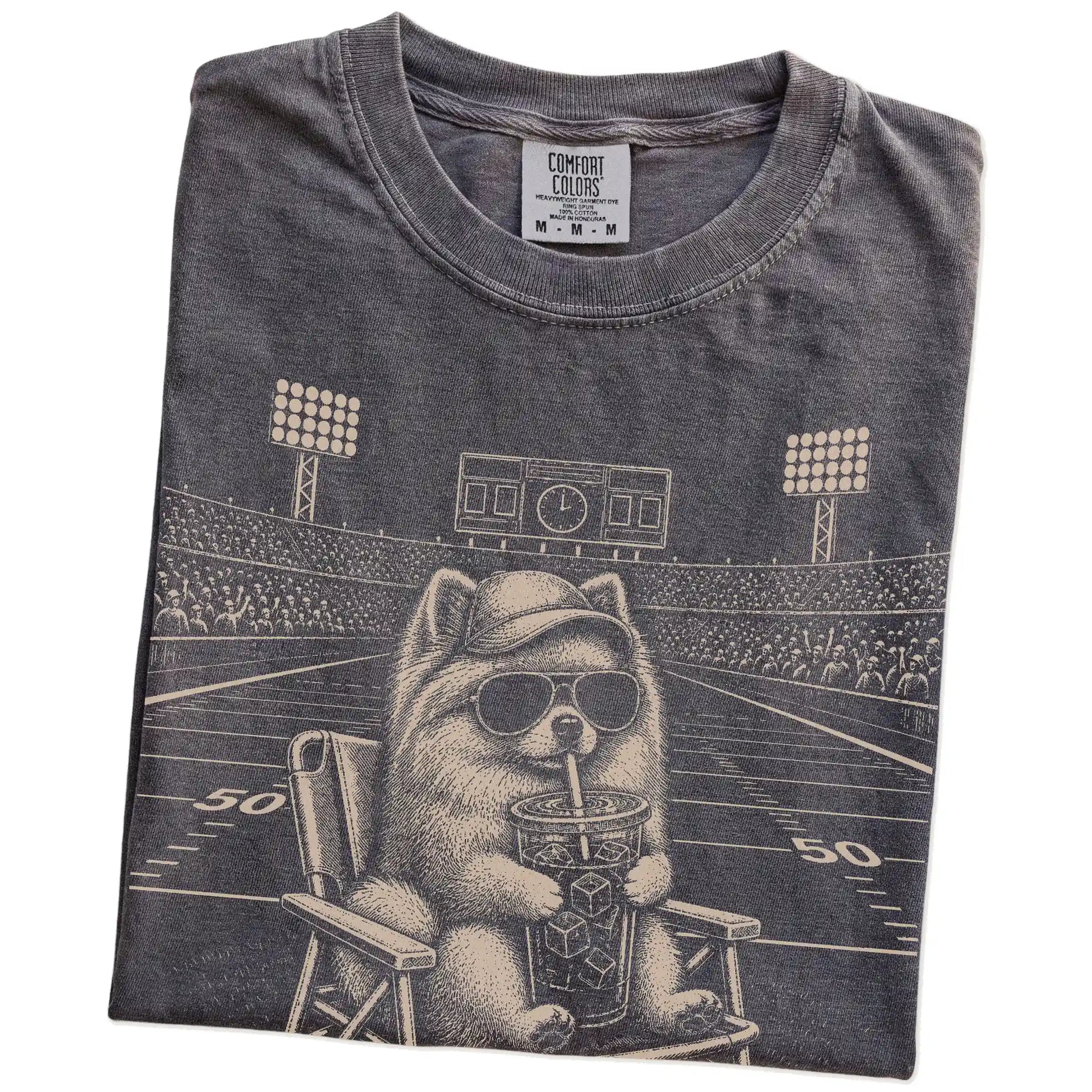 Folded Pepper Comfort Colors® T-shirt showing Pomeranian claiming the football field with “I Live Here Now” lettering