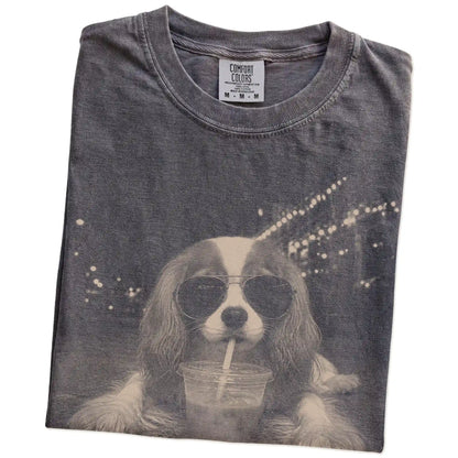 Folded Pepper Comfort Colors® T-shirt showing Cavalier King Charles Spaniel with iced coffee in a retro grunge design