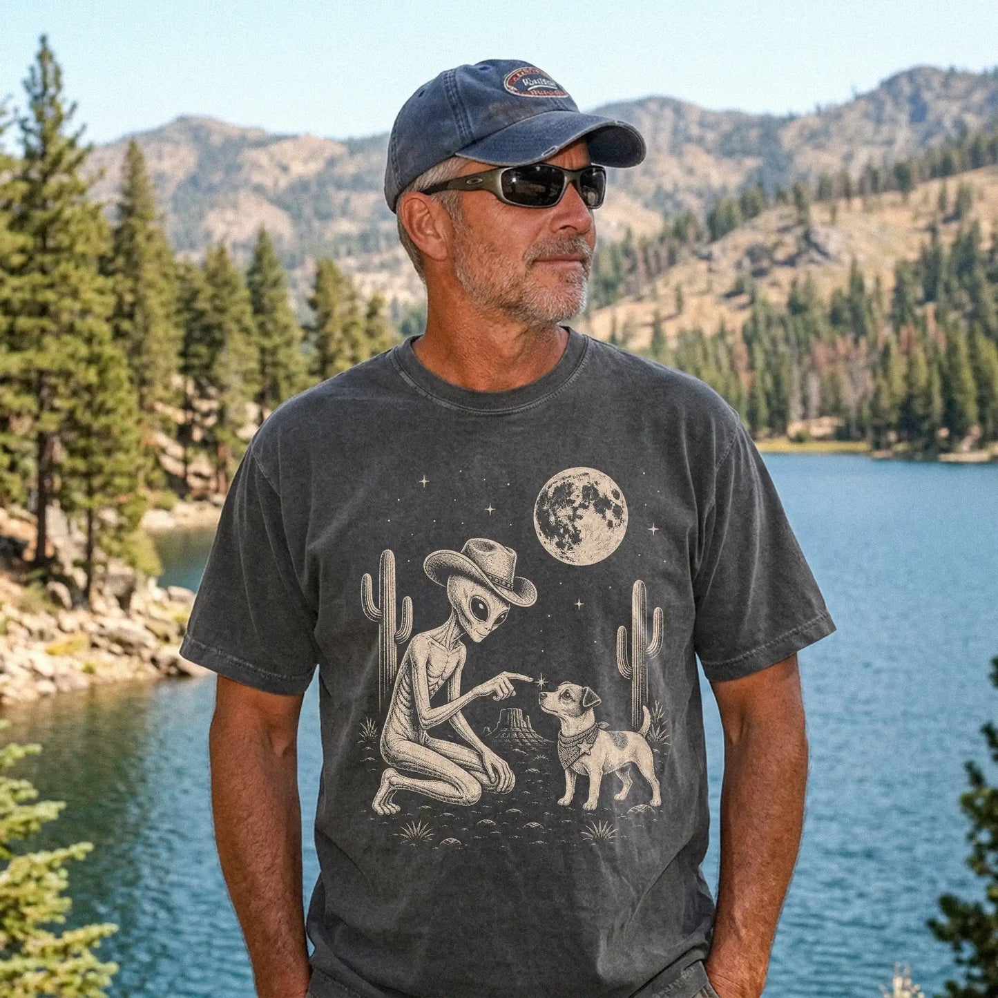 Model wearing a Pepper Comfort Colors® T-shirt with cowboy alien fist-bumping a jack russell beneath the moon