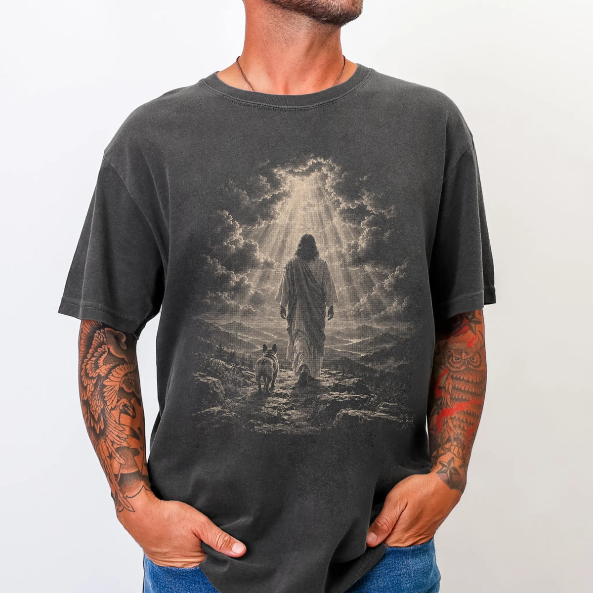 Person wearing a Pepper T-shirt with Jesus walking beside a French Bulldog beneath rays of light