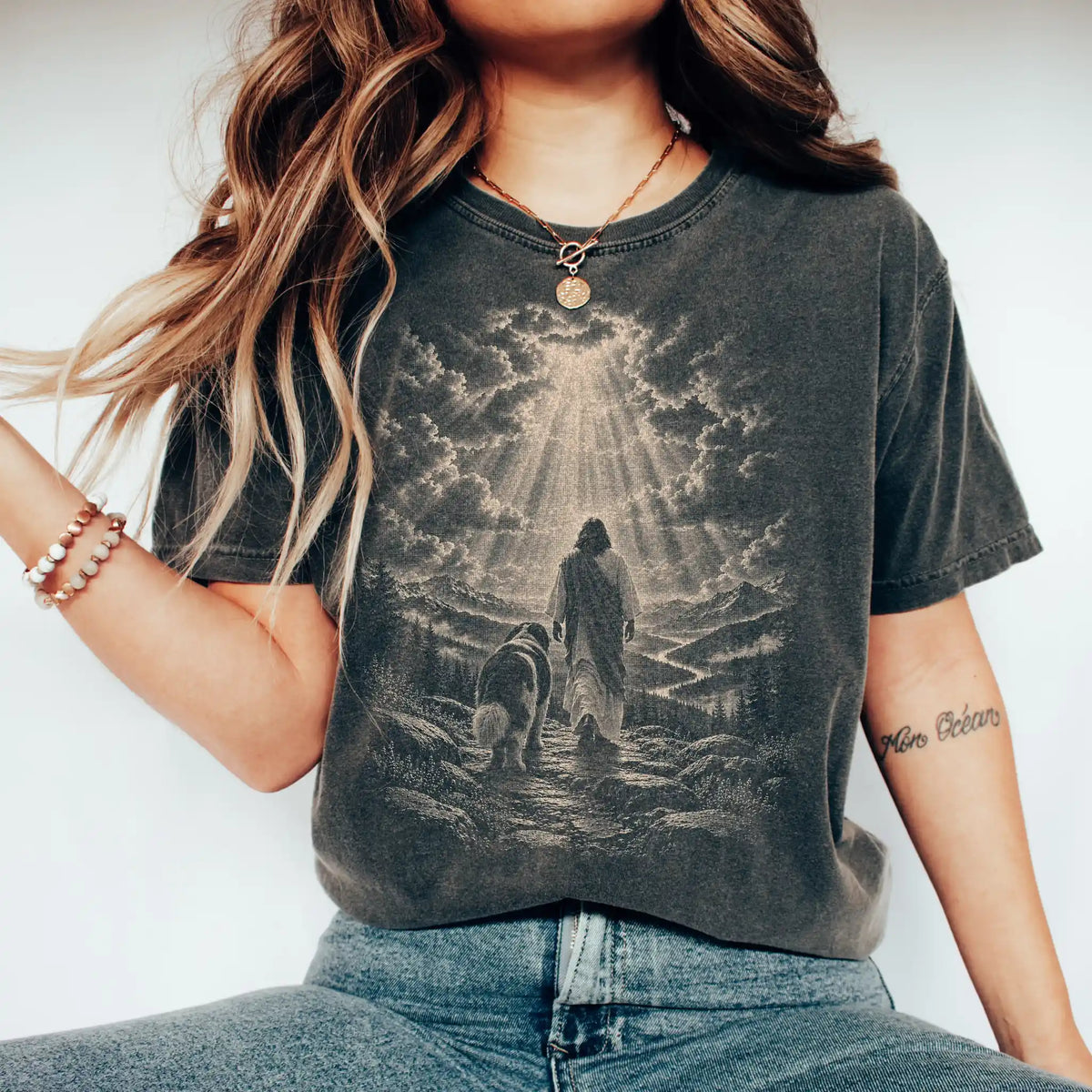 Person wearing a Pepper T-shirt with Jesus walking beside a St Bernard beneath rays of light