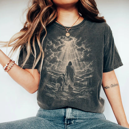 Person wearing a Pepper T-shirt with Jesus walking beside a St Bernard beneath rays of light