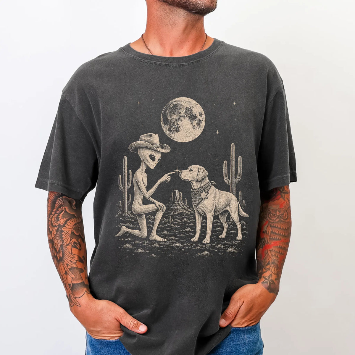 Model wearing a Pepper Comfort Colors® T-shirt with cowboy alien fist-bumping a labrador retriever beneath the moon