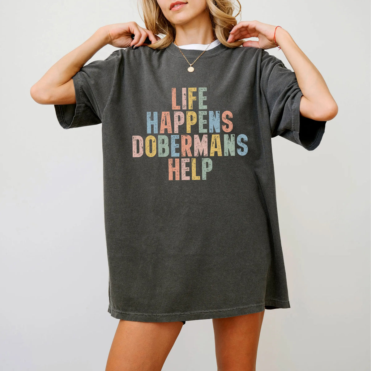 Model wearing a Pepper Comfort Colors® T-shirt featuring Doberman making hard days better with “Life Happens, Dogs Help” lett
