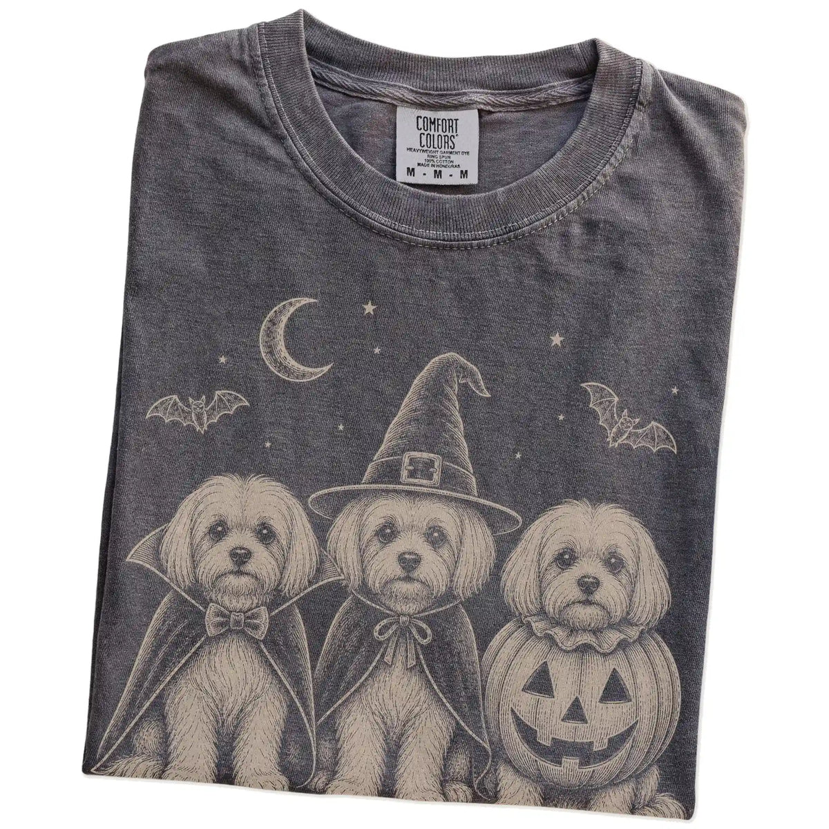 Folded Pepper Comfort Colors® T-shirt showing three Maltese dogs dressed for Halloween beneath bats and a crescent moon