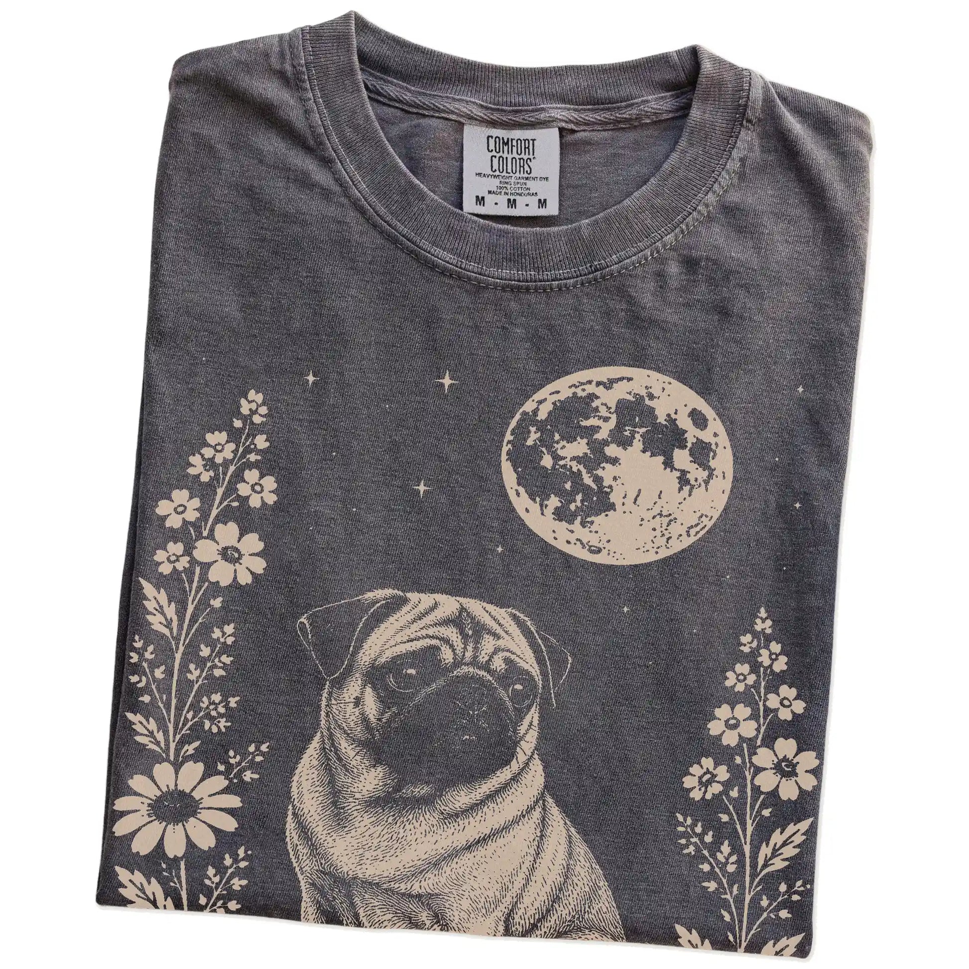 Folded Pepper Comfort Colors® T-shirt showing Pug framed by flowers beneath the moon