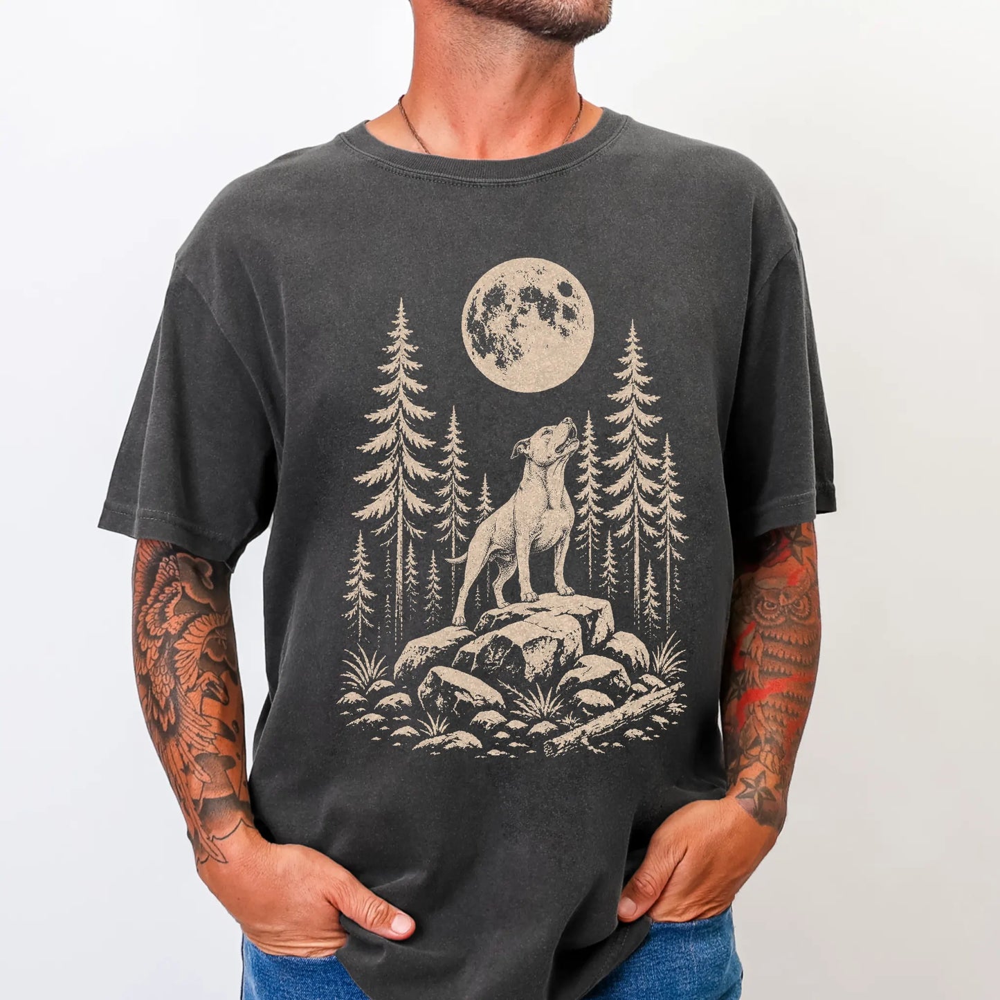 Model wearing a Pepper Comfort Colors® T-shirt with a Pitbull howling beneath the moon and pine trees