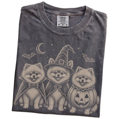 Folded Pepper Comfort Colors® T-shirt showing three Pomeranian dogs dressed for Halloween beneath bats and a crescent moon