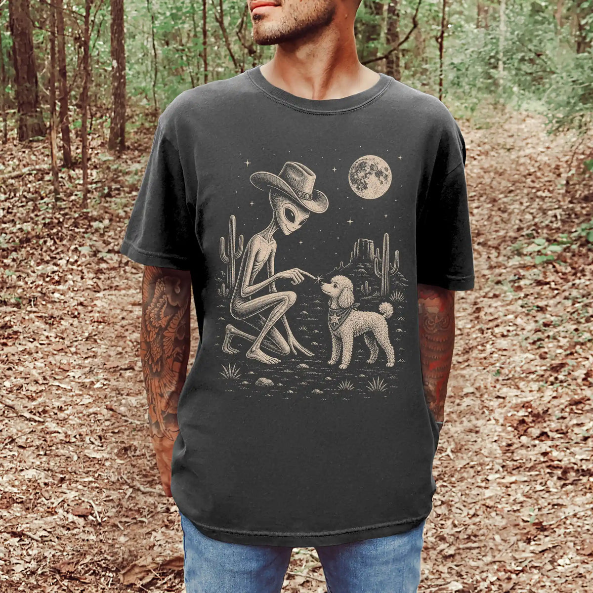 Model wearing a Pepper Comfort Colors® T-shirt with cowboy alien fist-bumping a poodle beneath the moon