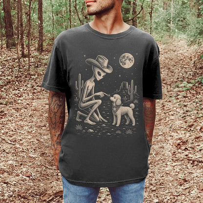 Model wearing a Pepper Comfort Colors® T-shirt with cowboy alien fist-bumping a poodle beneath the moon