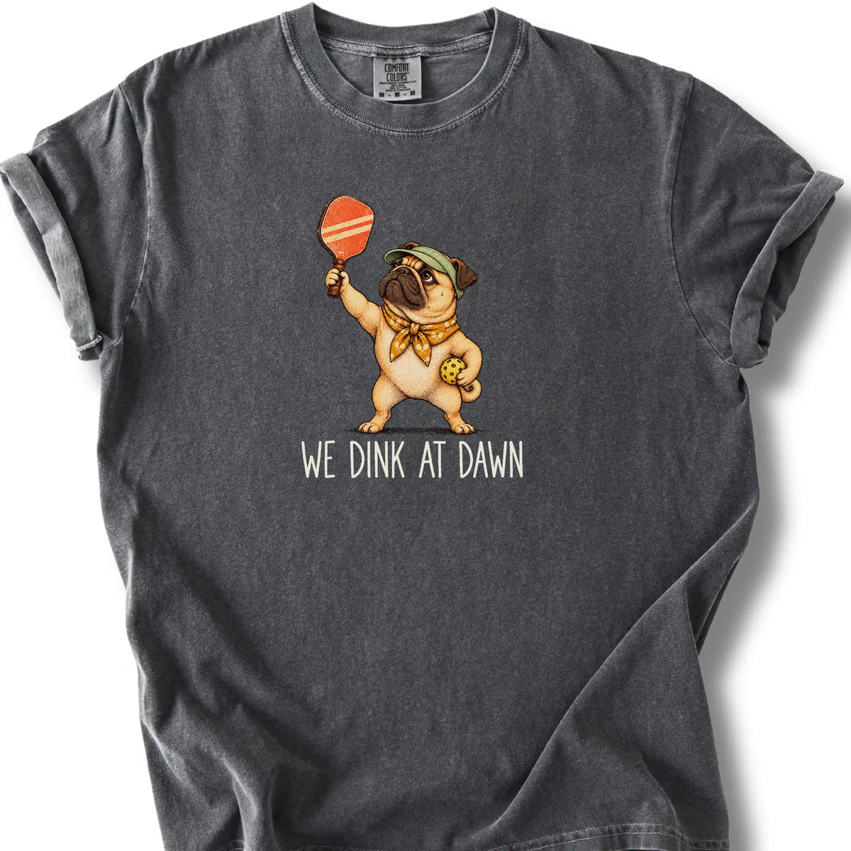 Pug with a pickleball paddle and ball on a Pepper Comfort Colors® T-shirt with We Dink at Dawn text