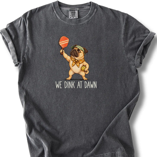 Pug with a pickleball paddle and ball on a Pepper Comfort Colors® T-shirt with We Dink at Dawn text