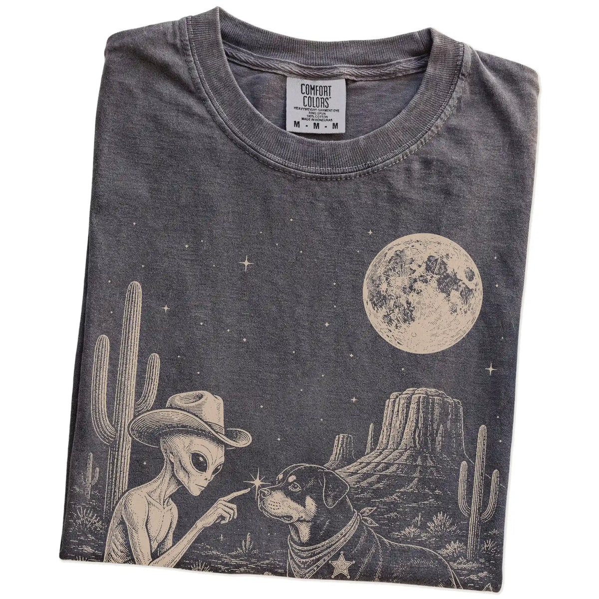 Folded Pepper Comfort Colors® T-shirt showing cowboy alien fist-bumping a rottweiler beneath the moon
