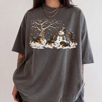Rottweiler puppies playing in snow with a snowman on a Pepper T-shirt worn by a model