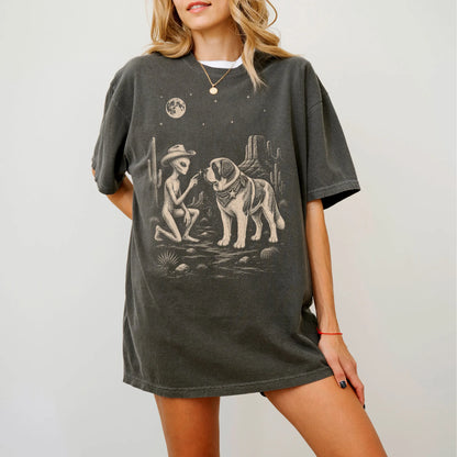 Model wearing a Pepper Comfort Colors® T-shirt with cowboy alien fist-bumping a saint bernard beneath the moon