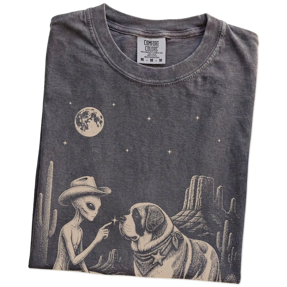 Folded Pepper Comfort Colors® T-shirt showing cowboy alien fist-bumping a saint bernard beneath the moon