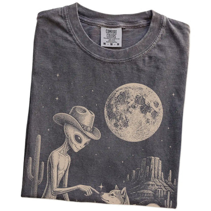 Folded Pepper Comfort Colors® T-shirt showing cowboy alien fist-bumping a shiba inu beneath the moon