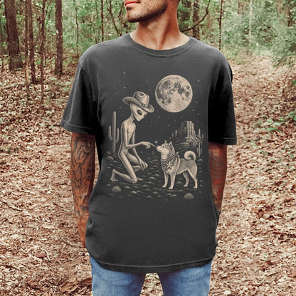 Model wearing a Pepper Comfort Colors® T-shirt with cowboy alien fist-bumping a shiba inu beneath the moon