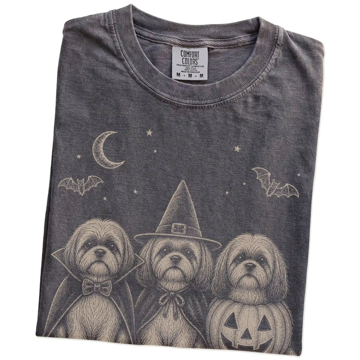 Folded Pepper Comfort Colors® T-shirt showing three Shih Tzu dogs dressed for Halloween beneath bats and a crescent moon