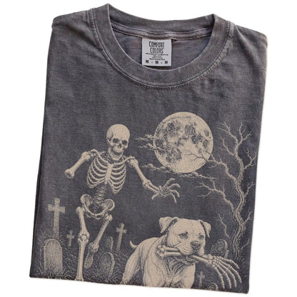 Folded Pepper Comfort Colors® T-shirt showing American Bulldog running through a moonlit graveyard with a chasing skeleton