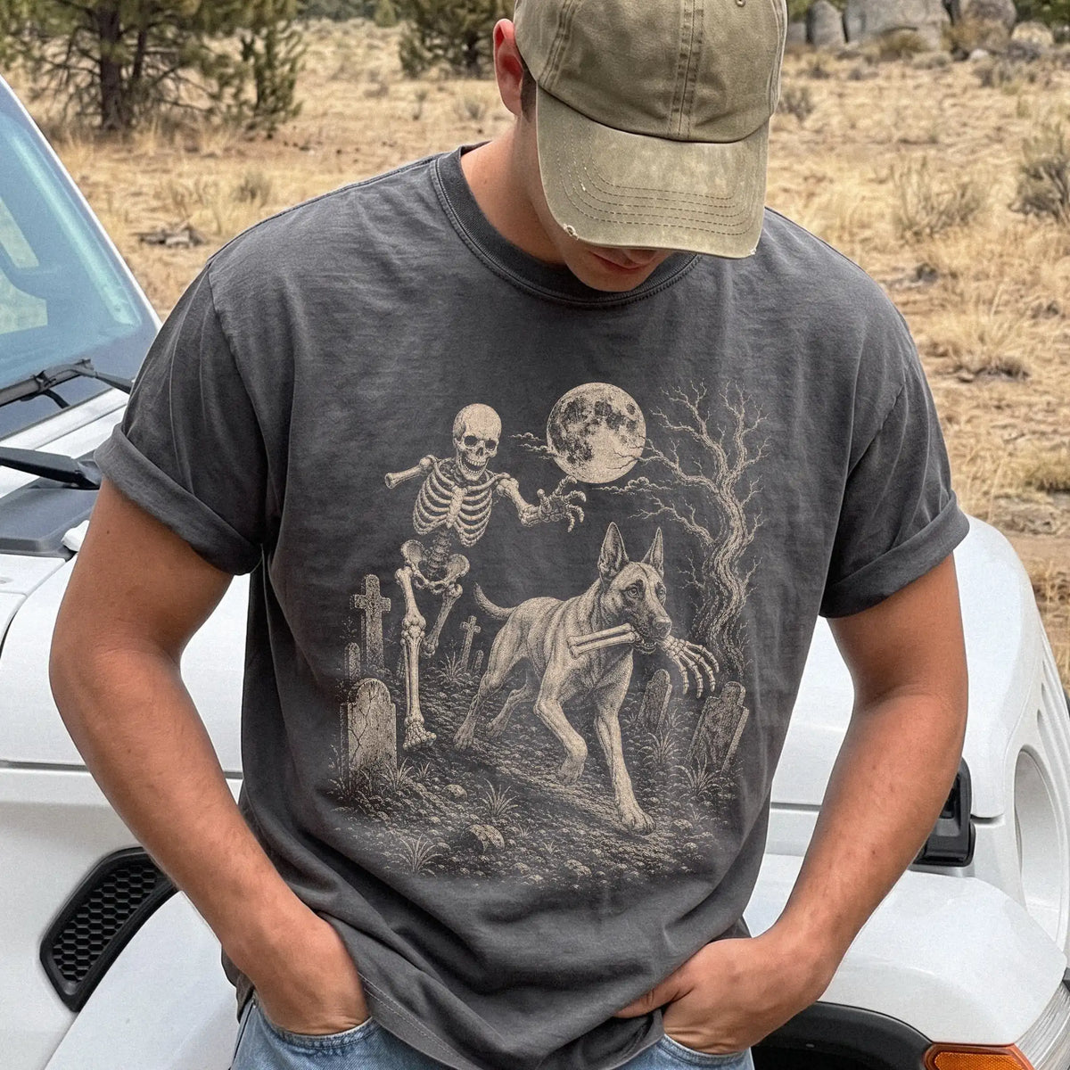 Model wearing a Pepper Comfort Colors® T-shirt showing Belgian Malinois running through a moonlit graveyard with a chasing sk