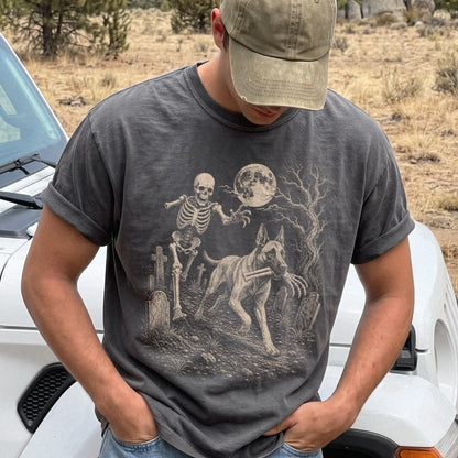 Model wearing a Pepper Comfort Colors® T-shirt showing Belgian Malinois running through a moonlit graveyard with a chasing sk
