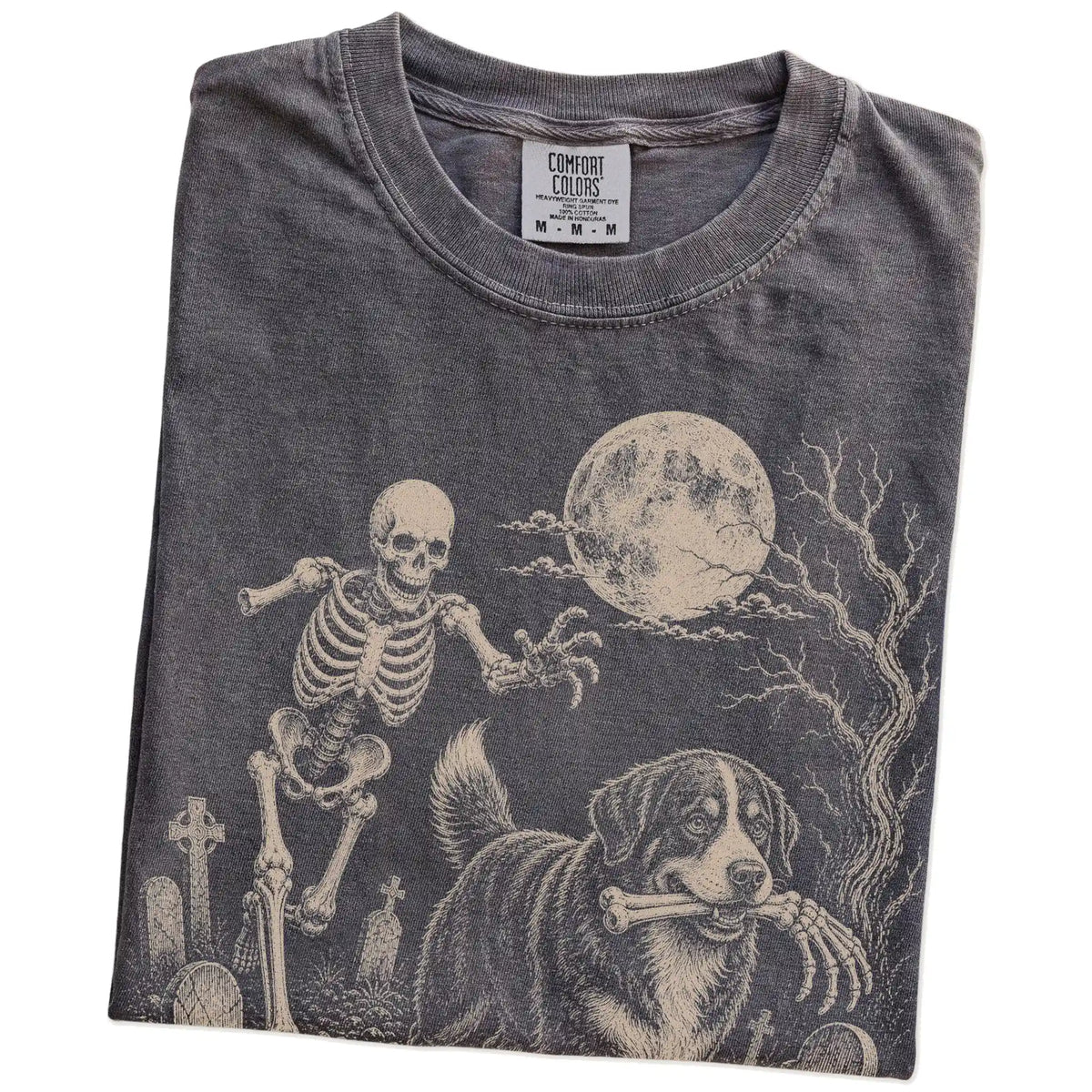 Folded Pepper Comfort Colors® T-shirt showing Bernese Mountain Dog running through a moonlit graveyard with a chasing skeleto
