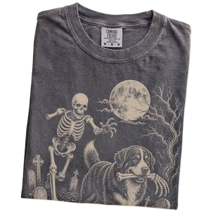 Folded Pepper Comfort Colors® T-shirt showing Bernese Mountain Dog running through a moonlit graveyard with a chasing skeleto