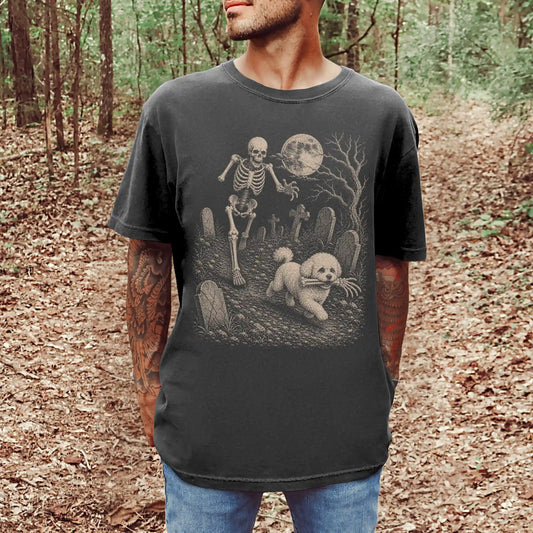 Model wearing a Pepper Comfort Colors® T-shirt showing Bichon Frise running through a moonlit graveyard with a chasing skelet