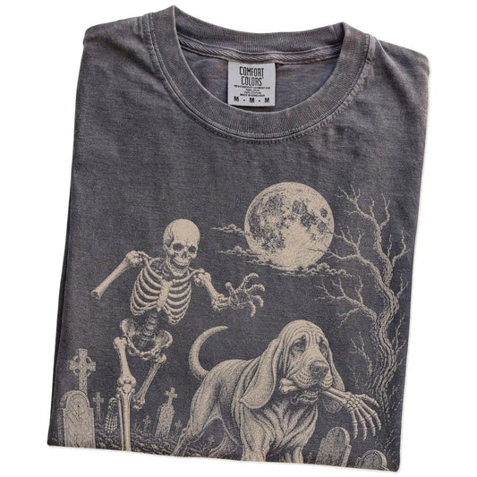 Folded Pepper Comfort Colors® T-shirt showing Bloodhound running through a moonlit graveyard with a chasing skeleton