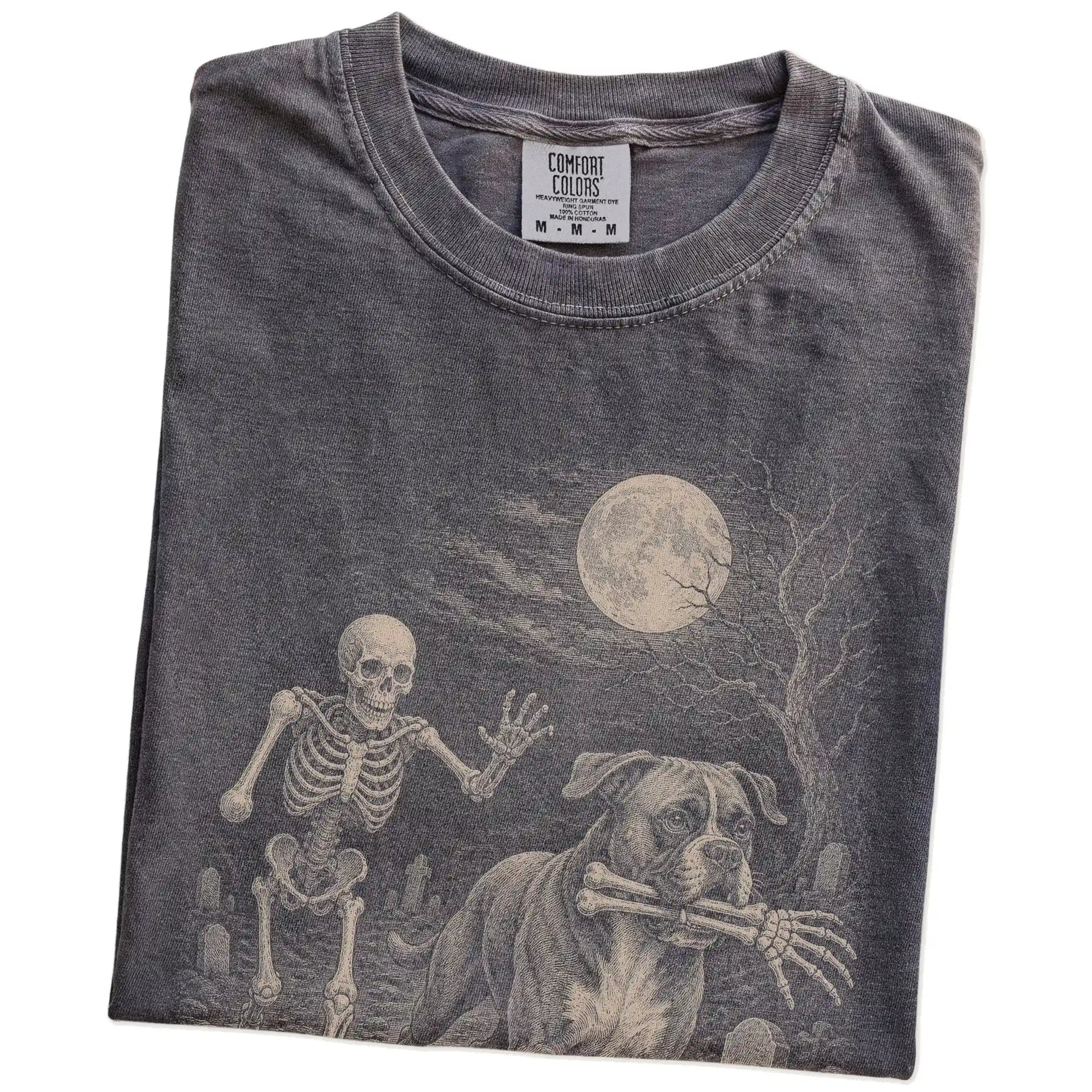 Folded Pepper Comfort Colors® T-shirt showing Boxer running through a moonlit graveyard with a chasing skeleton