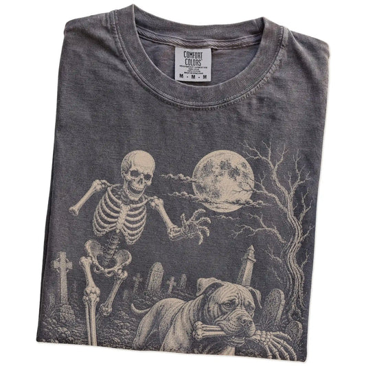 Folded Pepper Comfort Colors® T-shirt showing Cane Corso running through a moonlit graveyard with a chasing skeleton