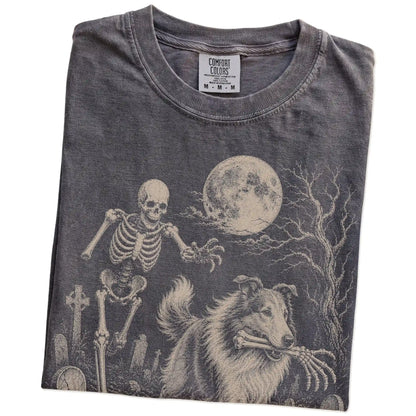 Folded Pepper Comfort Colors® T-shirt showing Collie running through a moonlit graveyard with a chasing skeleton