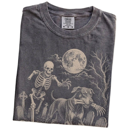 Folded Pepper Comfort Colors® T-shirt showing Doberman running through a moonlit graveyard with a chasing skeleton
