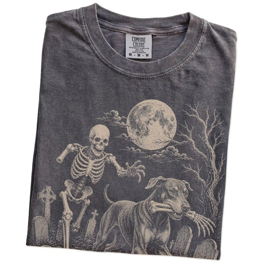Folded Pepper Comfort Colors® T-shirt showing Doberman running through a moonlit graveyard with a chasing skeleton