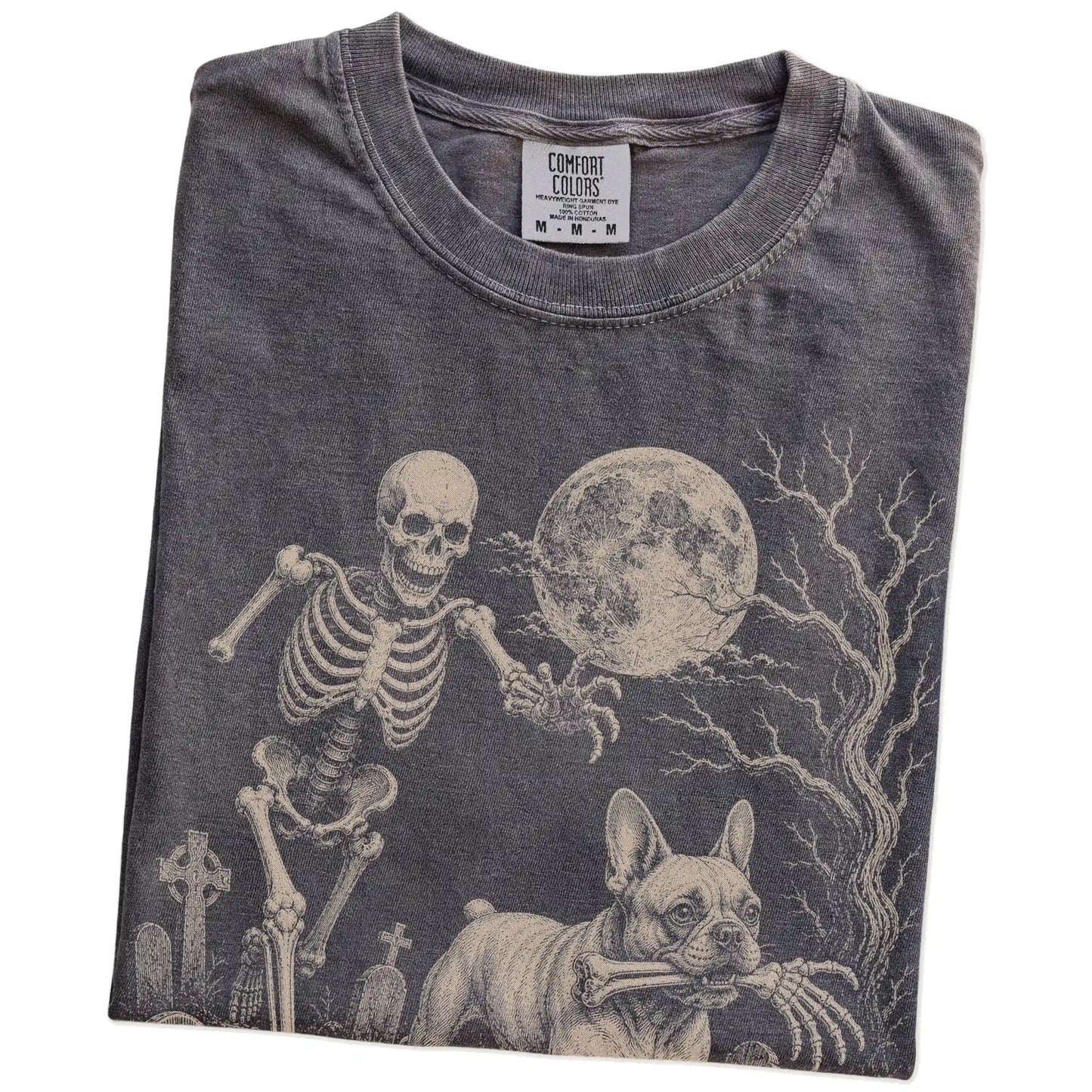 Folded Pepper Comfort Colors® T-shirt showing French Bulldog running through a moonlit graveyard with a chasing skeleton