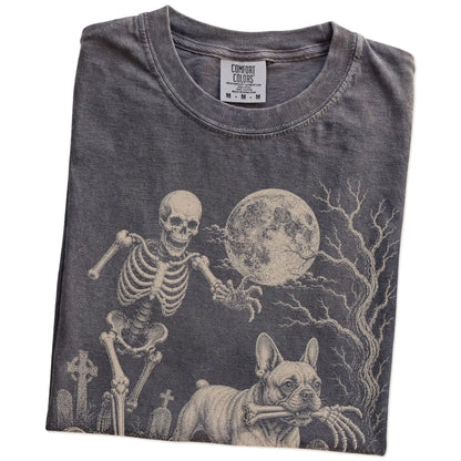 Folded Pepper Comfort Colors® T-shirt showing French Bulldog running through a moonlit graveyard with a chasing skeleton
