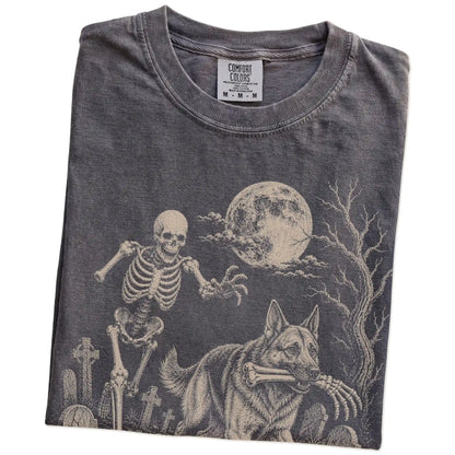 Folded Pepper Comfort Colors® T-shirt showing German Shepherd running through a moonlit graveyard with a chasing skeleton