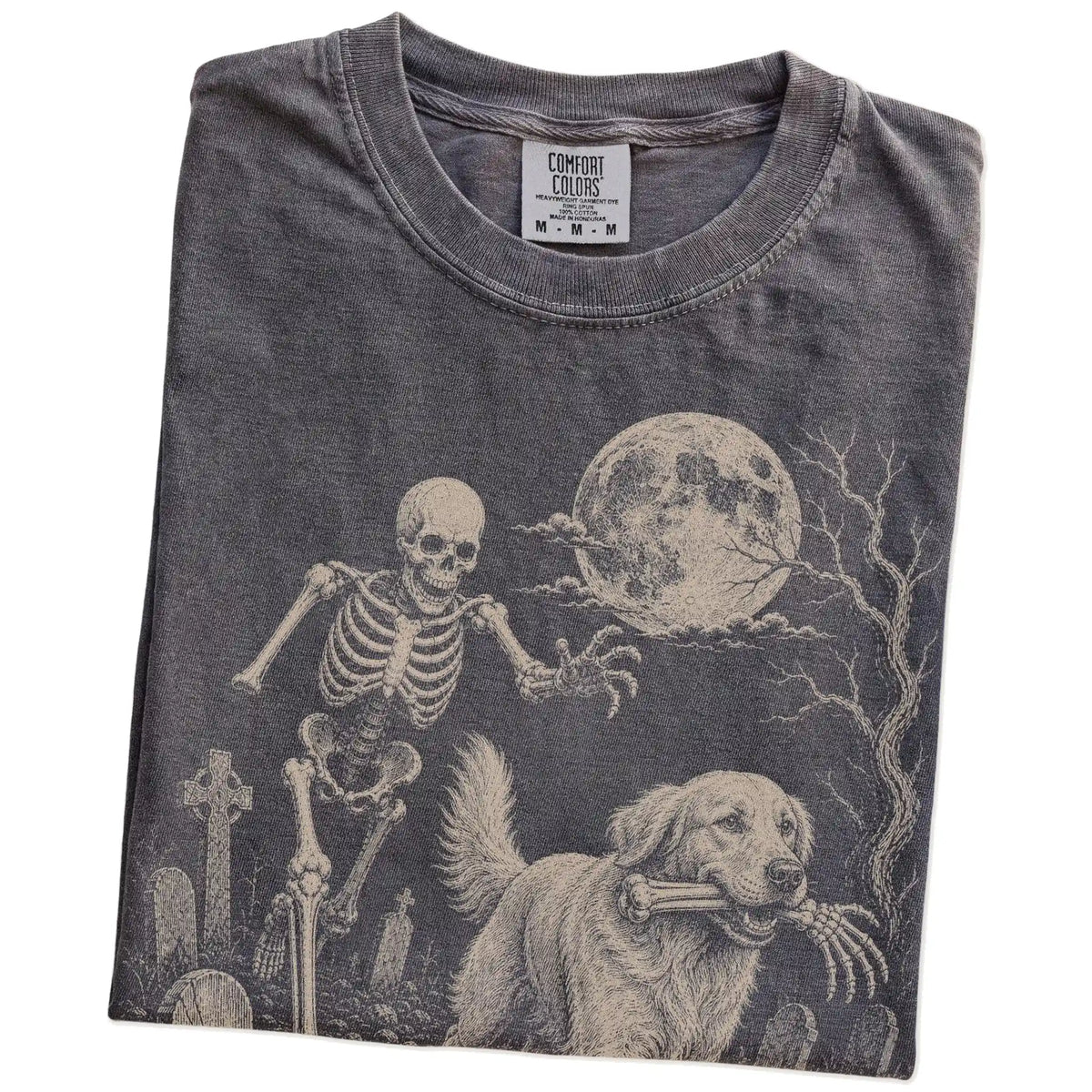 Folded Pepper Comfort Colors® T-shirt showing Golden Retriever running through a moonlit graveyard with a chasing skeleton